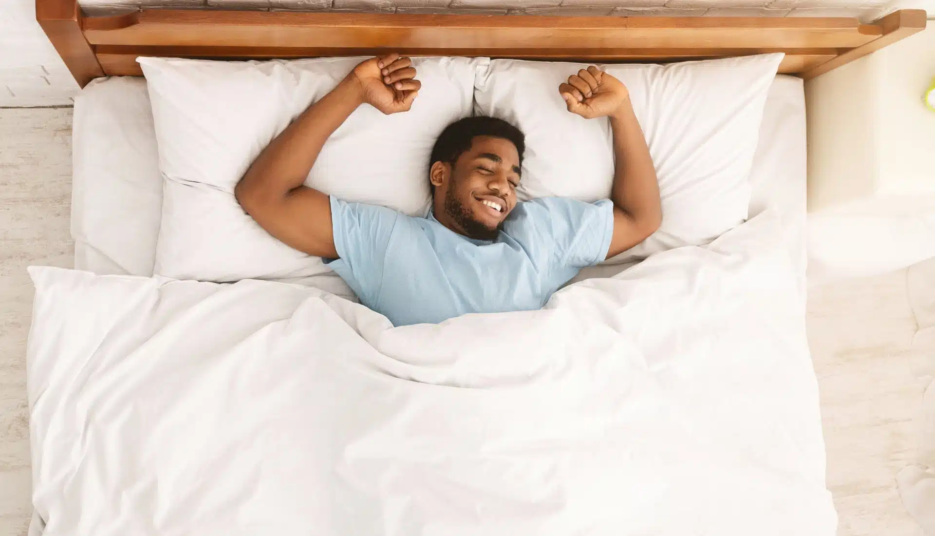 A young man who has treated his sleep apnea with OAT waking aup and and stretching in bed